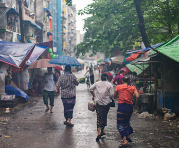 People walk through an informal market settlment whist its rains