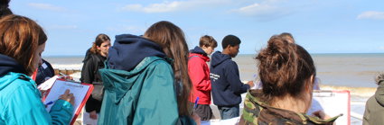 People standing by the sea holding clipboards and making notes