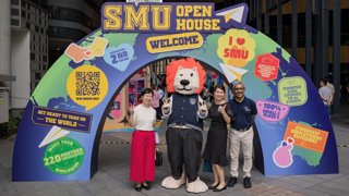 Three people posing with a univeristy mascot dressed as a lion.