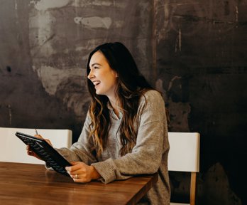 A woman sitting at a table holding a tablet