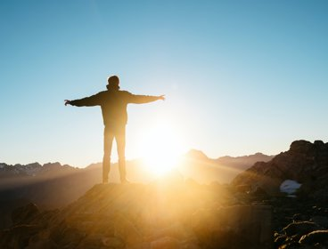 Person standing on a hill with arms outstretched