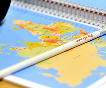 Close up of a pencil with the rgs website printed on it laying on a map.