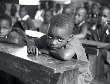 Grayscale photo of children sitting at desks in a classroom