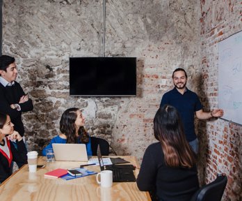 People sat around a table looking at a person presenting a workshop