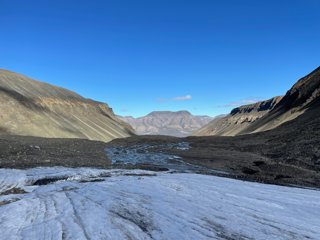 The edge of a glacier and meltwater in the base of a u-shaped valley. 