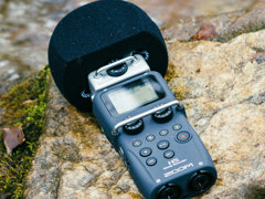 Hand-held microphone layingon a rock in a river.