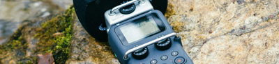 Hand-held microphone layingon a rock in a river.