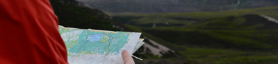 Person looks at map whilst standing in the the Scottish Highlands.