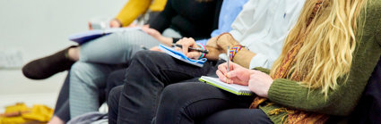 People with notebooks listening to a presentation
