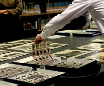 A researcher looking at sheets of historic photographic negatives