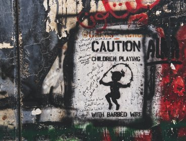 A sign saying 'Caution children playing with barbed wire'