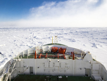 Looking out to the front of the SA Agulhas II ship sailing through the ocean in Antarctica, with pack ice all around