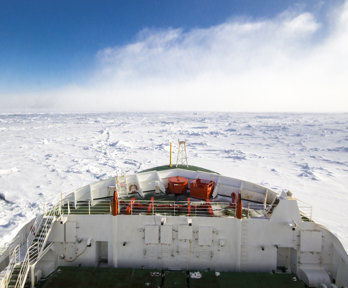 Looking out to the front of the SA Agulhas II ship sailing through the ocean in Antarctica, with pack ice all around
