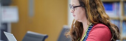 A young white woman working at a laptop