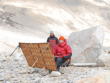 Tony Foster painting Mount Everest. A person next to Tony is looking at the painting.