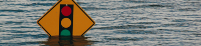 A traffic sign stands submerged in flood waters. the poll holding up the sign is completely submerged. 