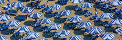 An aerial view of blue and white parasols and sun loungers on a sandy beach