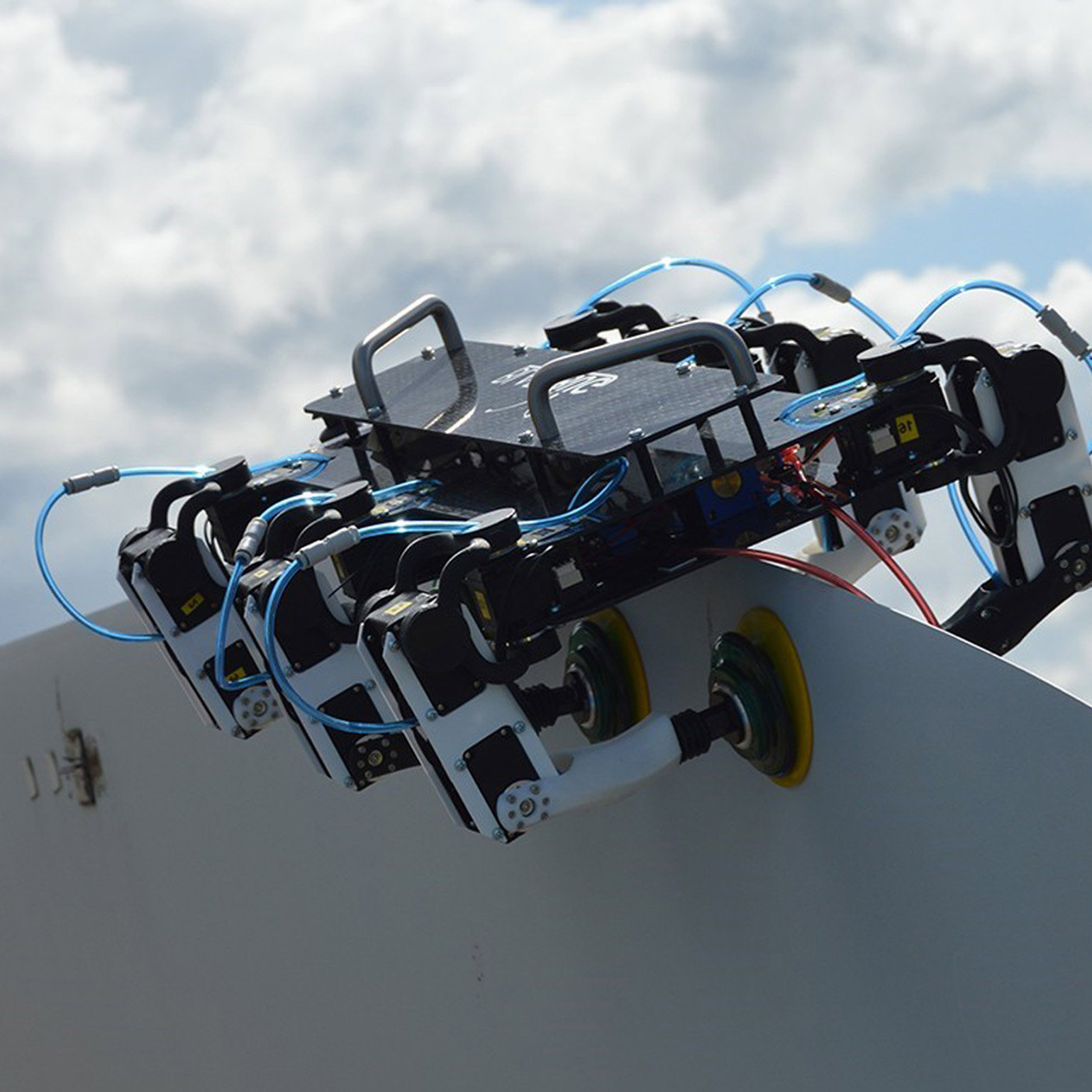 A robot contraption attached to a sheet of metal with suckers