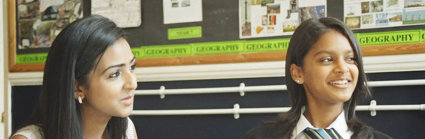 A student and teacher sitting together at a desk, looking at school work.