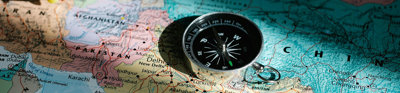 A modern compass laying on top of a world map.