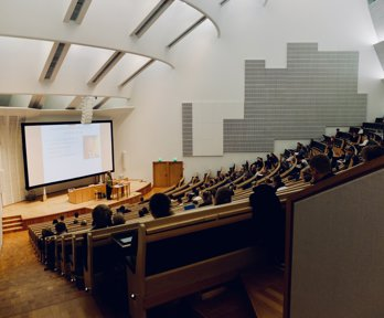 A lecture hall with rows of seats and studnetes