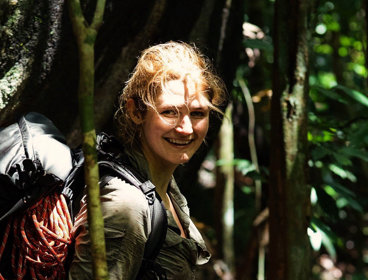 Explorer Lucy Shepherd in rainforest with filming equipment.