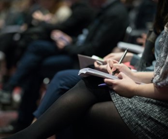 People taking notes at a conference