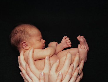 New born baby held with two hands. 