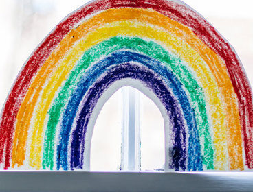 A drawn image of a rainbow, placed in a window.