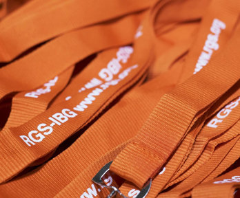 Pile of orange conference lanyards with white lettering reading RGS-IBG.