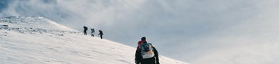 A group of people walk up a snowy steep mountain