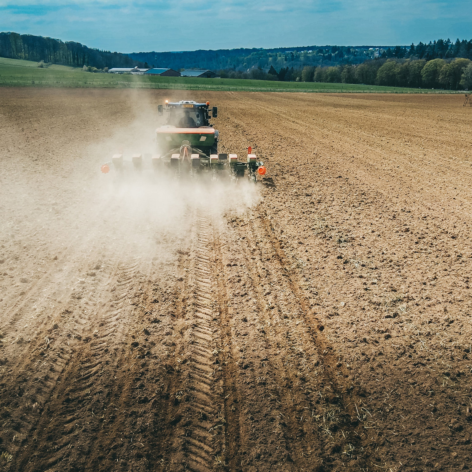 A tractor ploughing a field with a rural scene in the distance