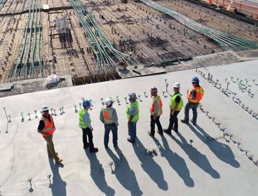 A group of people in high vis jackets standing on a roof top overlooking a building site