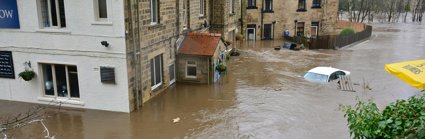 House surrounded by floodwater with submerged car