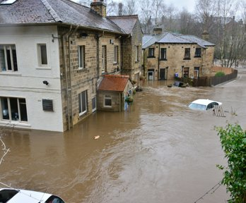 House surrounded by floodwater with submerged car