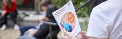 A person reading a conference programme.