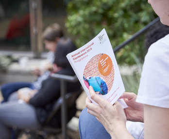 A person reading a conference programme.