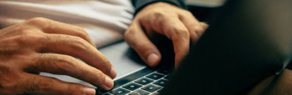 Person typing on a laptop which is resting on their lap.