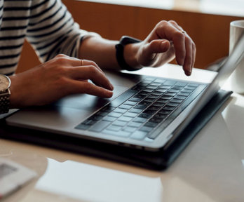 Person seated at the table using laptop.