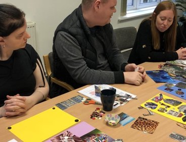  A group of people sitting at a table with pieces of artwork and craft supplies