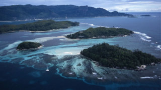 Aerial view of a natural submerged ridge and islands in an ocean. 