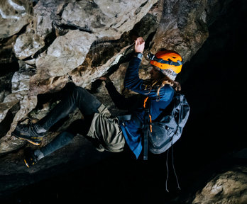 A woman who is rock climbing inside a cave.
