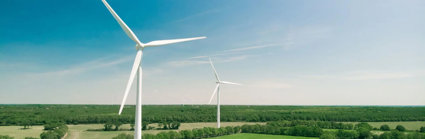 Two wind turbines in open fields with a clear sky. 