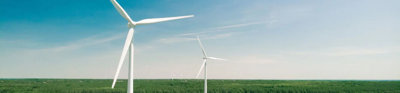 Two wind turbines in open fields with a clear sky. 