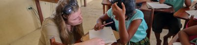 An adult helps a child with their school work in a school 