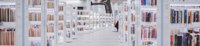 White book shelfs, neatly stacked with books fill the light grey interior of a minimalist library