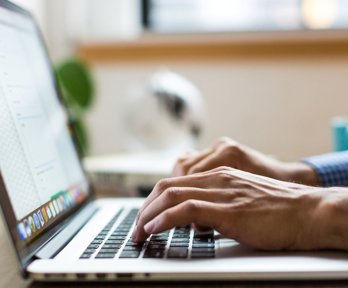 Person typing on laptop keyboard.