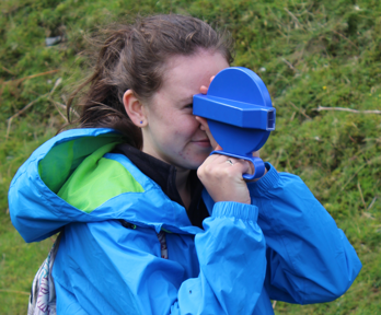 Girl in a blue coat using equipment to do geography fieldwork