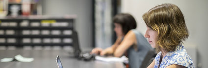 Person at a large table typing on a laptop.