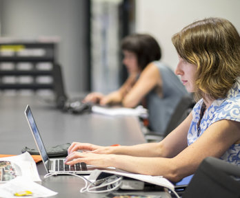 Person at a large table typing on a laptop.